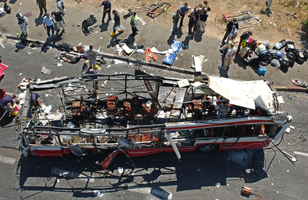 JERUSALEM, ISRAEL - JUNE 18: Israeli rescue workers tend to victims' bodies, lying on the pavement, at the scene of a Palestinian suicide bombing on a passenger bus in Jerusalem, June 18, 2002. At least 18 people were killed, some of them Jewish youth on the way to school, in the bombing. (Photo by Getty Images)