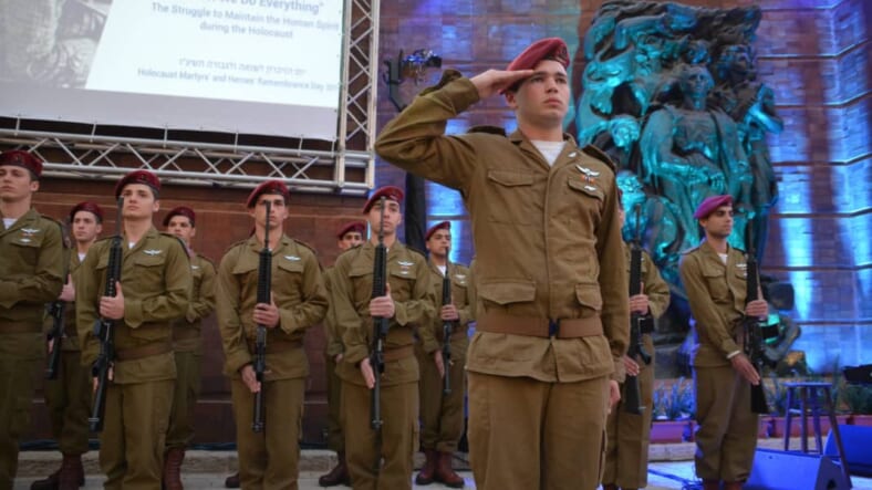 Honor guard at Yad Vashem for Yom HaShoah opening ceremony under sign with theme